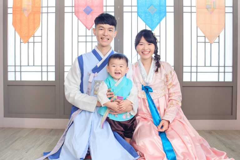 父母與寶寶穿著傳統韓服，在典雅韓式背景前展現幸福笑容。