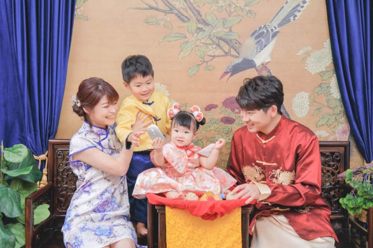 全家一起參與寶寶抓周儀式，寶寶坐在抓周椅上拿取道具，爸爸媽媽與哥哥穿著傳統服裝，溫馨記錄一歲成長時刻